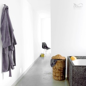 Łazienka z białymi ścianami, wanną, koszem na pranie i szlafrokiem.