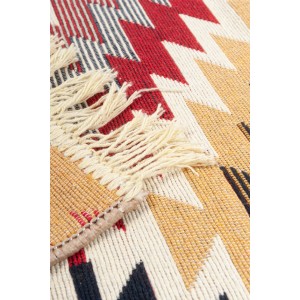 Zbliżenie dywanu z krótkim włosiem z frędzlami i geometrycznym wzorem w kolorze czerwonym, żółtym i czarnym.
