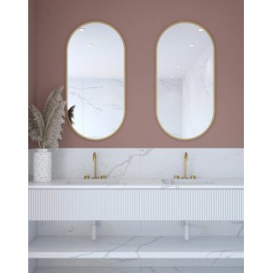 Dwa owalne lustra Lustra ze złotymi ramami nad podwójną umywalką.