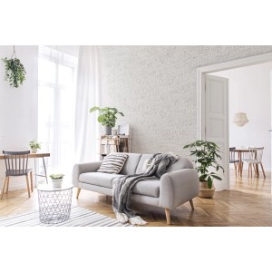 Jasny salon z szarą kanapą, dekoracyjnymi kamieniami na ścianie i drewnianą podłogą.