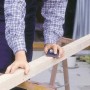 Rzemieślnik szlifuje drewno za pomocą ręcznego klocka ściernego LUX 70x130 mm. Prace szlifierskie z materiałami ściernymi.