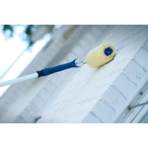 Wałek fasadowy LUX 25 cm z drążkiem teleskopowym podczas malowania ściany.