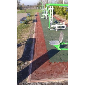 Zewnętrzne urządzenia fitness na czerwonej i zielonej nawierzchni bezpiecznej. Sprzęt do zabawy na placu zabaw.