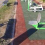 Zewnętrzne urządzenia fitness na czerwonej i zielonej nawierzchni bezpiecznej. Sprzęt do zabawy na placu zabaw.