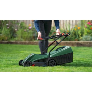 Zielona kosiarka na trawie. Elektryczna Kosiarka do ogrodu.