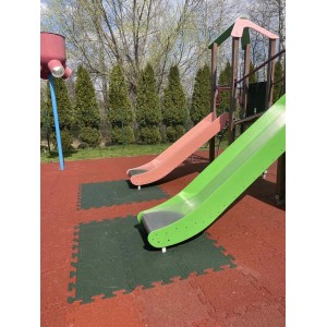 Plac zabaw ze zjeżdżalniami i matami amortyzującymi. Sprzęt do zabawy dla dzieci w ogrodzie lub parku.