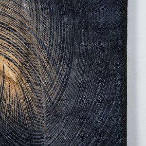 Zbliżenie dywanu z abstrakcyjnym wzorem pióra w kolorze złotym i ciemnoniebieskim.