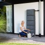 Szary zbiornik na deszczówkę 4rain Slim Stone Decor (330 l) z kobietą i konewką.