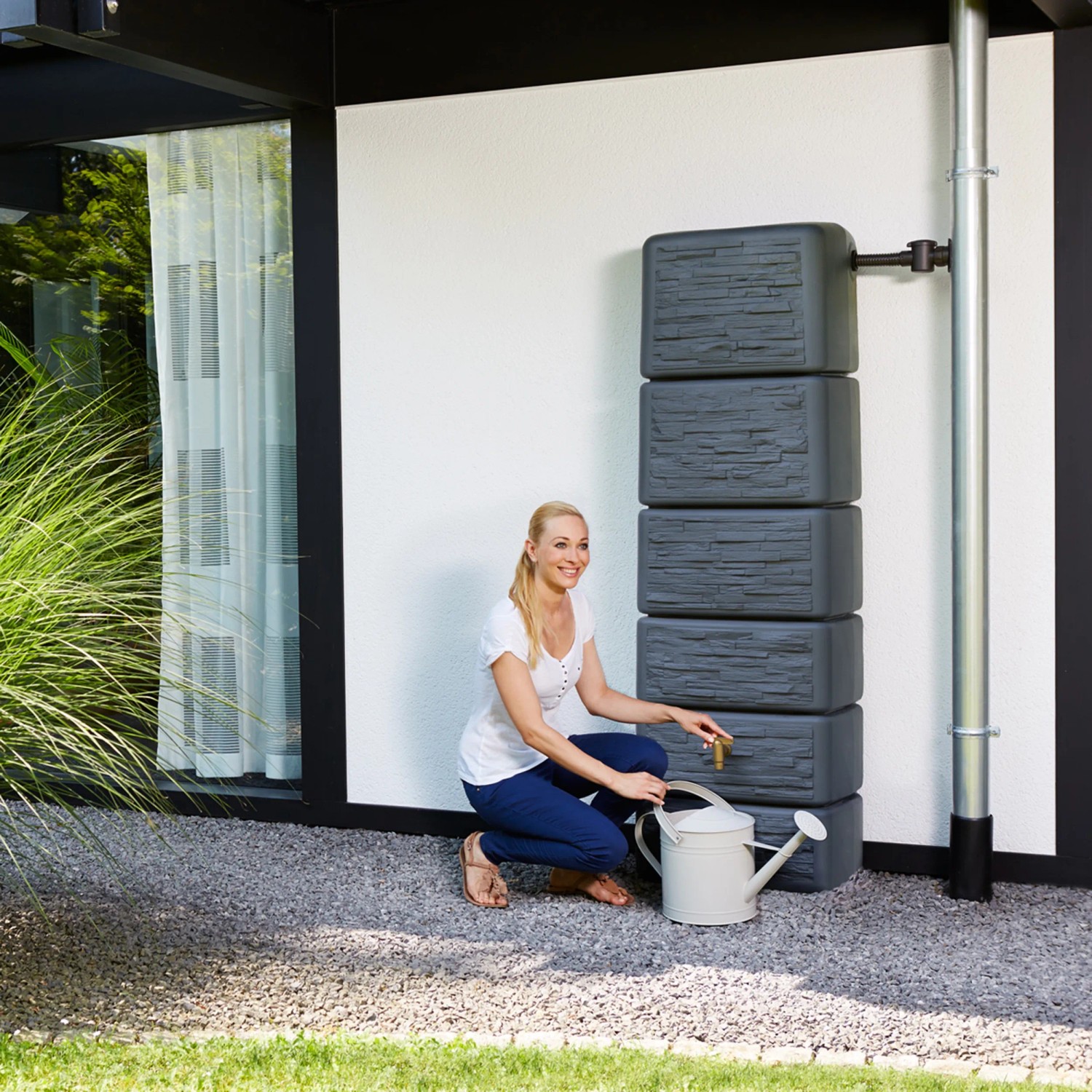 Szary zbiornik na deszczówkę 4rain Slim Stone Decor (330 l) z kobietą i konewką.