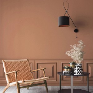 Pokój dzienny w kolorze terakoty z farbą do ścian t.b.t., fotelem, stołem i lampą.