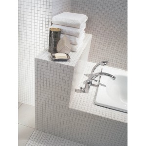 Łazienka z białymi mozaikami t.b.t., ręcznikami i wanną.