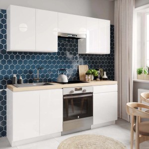 Nowoczesny biały zestaw mebli kuchennych ze zlewem, płytą grzewczą i szafkami wiszącymi na tle niebieskich sześciokątnych płytek.