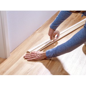 Nakładanie taśmy montażowej Tesa do tapet i tynku na listwę drewnianą.