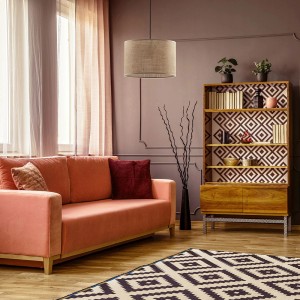 Beżowa lampa wisząca t.b.t. w salonie nad sofą i dywanem.