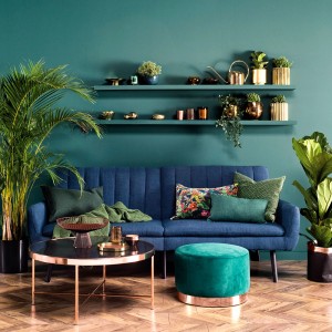 Salon z niebieską sofą, zieloną farbą na ścianach i elementami dekoracyjnymi. Kolorowe farby do ścian dla przytulnej atmosfery.