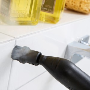 Oczyszczacz parowy Kärcher z okrągłą szczotką podczas czyszczenia fug płytek w łazience.