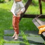 Dziecko bawi się na zielonych płytach placu zabaw w ogrodzie. Kategoria: Dalszy sprzęt do zabawy.