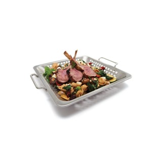 Wok Broil King ze stali nierdzewnej z dziurkami, wypełniony warzywami i kotletami jagnięcymi.
