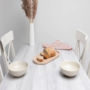 Stół z folią imitującą drewno, udekorowany chlebem, miskami i wazonem.