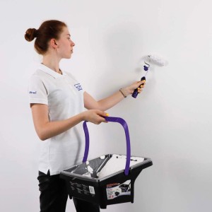 Kobieta maluje ścianę wałkiem i wiadrem z farbą. Kategoria: Wałki malarskie.