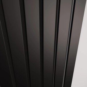 Zbliżenie czarnego grzejnika t.b.t. z pionowymi lamelami.