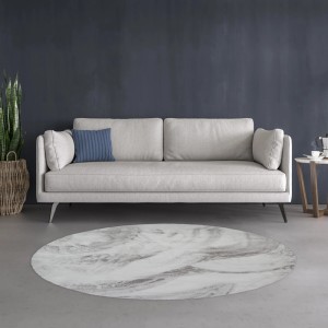 Okrągły, marmurkowy dywan z długim włosiem w kolorze białym i szarym przed sofą.