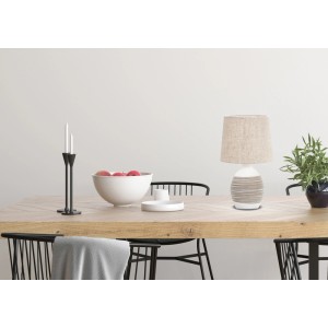 Dekoracyjna lampa stołowa z beżowym abażurem na drewnianym stole.