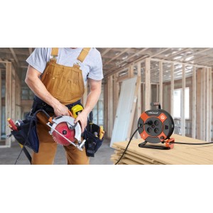 Pomarańczowo-czarny przedłużacz na bębnie z budowlańcem w tle.