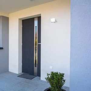 t.b.t. Zewnętrzny reflektor LED zamontowany na ścianie domu obok drzwi.