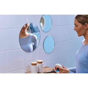 Kobieta mocuje lustro t.b.t. do ściany za pomocą taśmy. Lustra samoprzylepne.