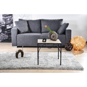 Szara sofa z elementami dekoracyjnymi, takimi jak stół, lampa i dywan w salonie.