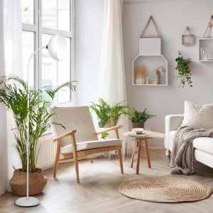 Biała lampa podłogowa w salonie z fotelem i roślinami.