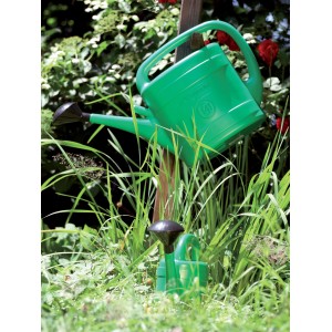 Zielona konewka w ogrodzie. Konewka do podlewania ogrodu.