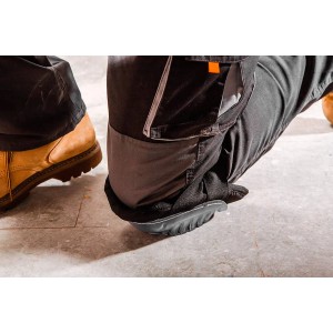 Zbliżenie: Klęcząca osoba w spodniach roboczych t.b.t. i nakolannikach.