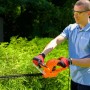 Mężczyzna przycina żywopłot elektrycznymi nożycami do żywopłotu t.b.t.