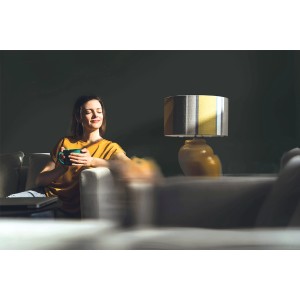 Kobieta relaksuje się z filiżanką na sofie, lampa w tle. Farba do ścian: t.b.t.