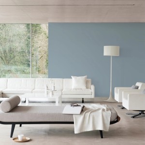 Salon z niebieską pomalowaną ścianą, białą kanapą i jasną podłogą. Kolorowa farba do ścian wewnętrznych.