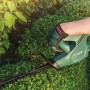 Akumulatorowe nożyce do żywopłotu podczas cięcia żywopłotu. Zielone, z akumulatorem.