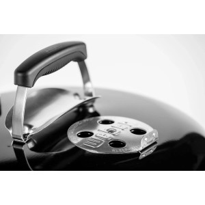 Zbliżenie grilla węglowego z pokrywą i suwakiem wentylacyjnym.