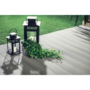 Szare deski tarasowe t.b.t. z dekoracyjnymi lampionami i rośliną w ogrodzie.