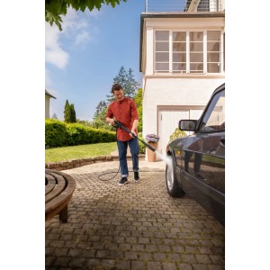 Mężczyzna czyści samochód na zewnątrz za pomocą myjki ciśnieniowej t.b.t.