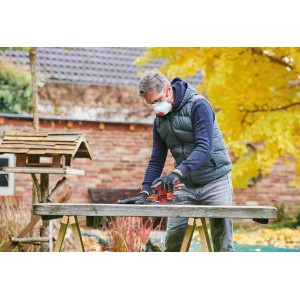 Mężczyzna szlifuje drewno szlifierką oscylacyjną akumulatorową Einhell TC-OS 18/187 Li Solo.