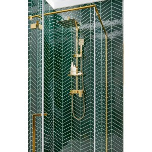 Zielone płytki w jodełkę ze złotą armaturą prysznicową. Dekoracje do łazienki.