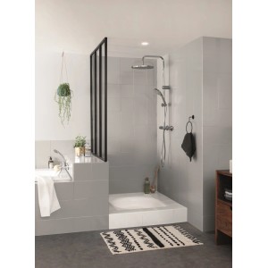 Nowoczesna łazienka z szarymi płytkami, prysznicem, wanną i wzorzystym dywanikiem łazienkowym.