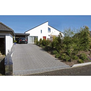 Podjazd z odwodnieniem liniowym. Szara kostka brukowa i nowoczesny dom w tle.