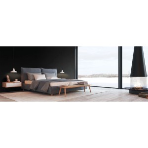 Sypialnia z szarym łóżkiem, szafką nocną i kominkiem przed dużym oknem.