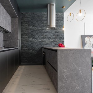 Nowoczesna kuchnia z szarymi kamieniami dekoracyjnymi t.b.t. na ścianie i wyspą kuchenną.