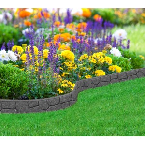 Szara obrzeże trawnikowe t.b.t. z tworzywa sztucznego na rabacie kwiatowej.
