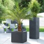 Kolumna na rośliny Scheurich C-Cube High, Ø 26 cm, Stony Black, z palmą i innymi roślinami w ogrodzie.