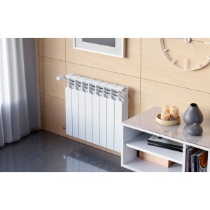Biały grzejnik t.b.t. zamontowany na ścianie. Ogrzewanie do pomieszczeń mieszkalnych.